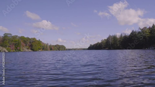 Boating slowly on lake McKellar Ontario in early fall, approaching a bridge in the distance photo