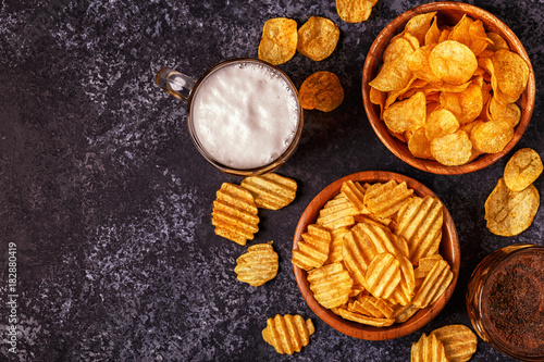 Beer and crispy potato chips on stone background.