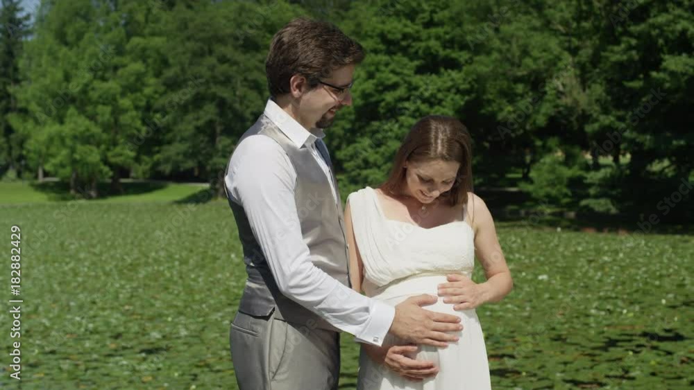 SLOW MOTION CLOSE UP: Expecting parents smile as they feel their baby kicking for the first time. Man and woman lovingly gaze at each other. Smiling husband and wife enjoy the wonders of pregnancy. SLOW MOTION CLOSE UP: Expecting parents smile as they feel their baby kicking for the first time. Man and woman lovingly gaze at each other. Smiling husband and wife enjoy the wonders of pregnancy.