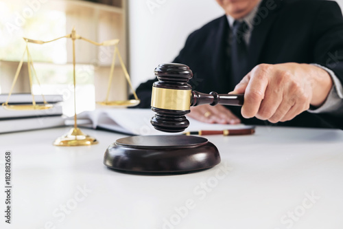 Close up of Male lawyer or judge hand's striking the gavel on sounding block, working with Law books, report the case on table in modern office, Law and justice concept
