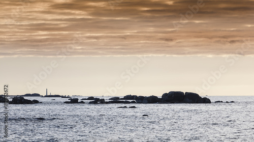 Damatic lights coastline in Brittany, France in sunset with a lighthouse