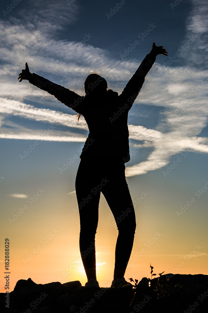 Fototapeta premium Silhouette of a standing with her hands up as the sign of happiness