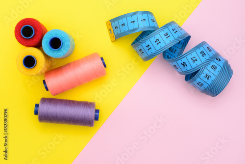 tool kit for cutting, sewing on yellow and pink background with a blank space under an inscription in the middle. Top view, Flat Lay. fashion minimalism