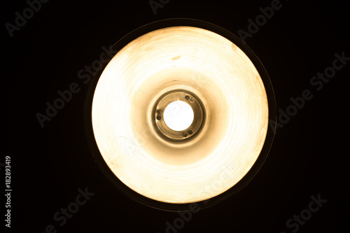 Metalic vintage ceiling lamp closeup. Bright light bulb in round lamp. View from bottom. Vintage image color effect.