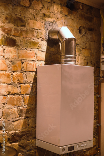 Home, flat gas boiler sysytem.  Gas heating system with a smoke outlet in the chimney. Attached to the brick wall. photo