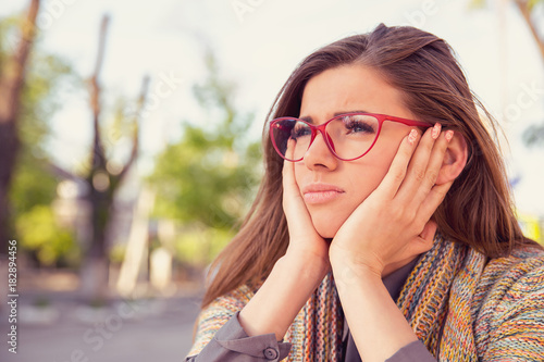 thoughtful sad young woman looking gloomy sitting outdoors