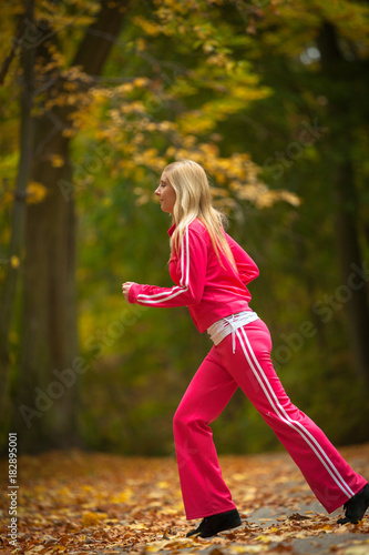 Blonde girl young woman running jogging in autumn fall forest park