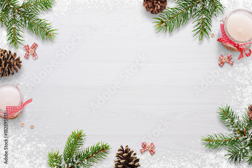 Flat Christmas background scene with fir branches, bows, candles, pinecones and snowflakes Free space for copy text on white board. Top view.