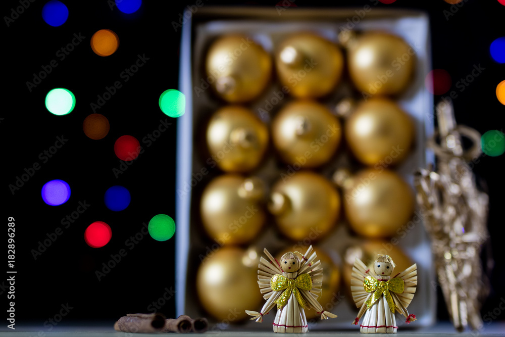 Naklejka premium Christmas baubles in a box against a background of Christmas lights. Christmas dinner wrapped in cardboard box on the background of the lamps.