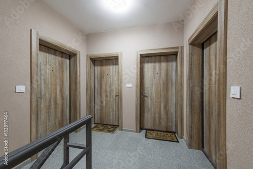 Four luxury wooden front doors in modern building coridor