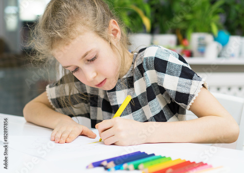 Little girl drawing with pencil at home. photo