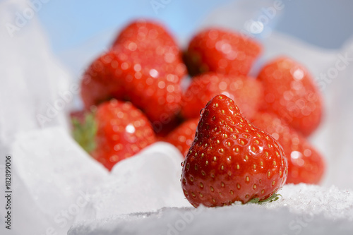 Fresh red strawberries are frozen on cold blue ice