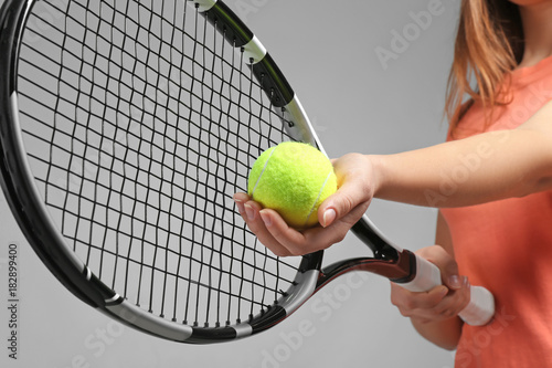 Woman with tennis racket and ball on grey background © Africa Studio