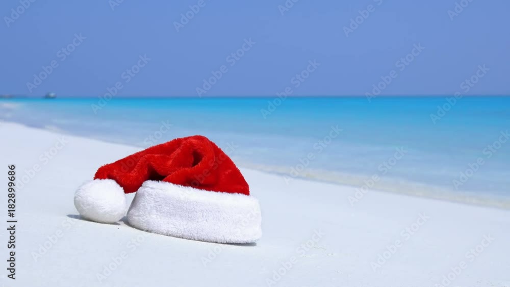 Christmas helper hat on tropical sandy beach with calm waves. Maldivian destination with nobody Christmas helper hat on tropical sandy beach with calm waves. Maldivian destination with nobody