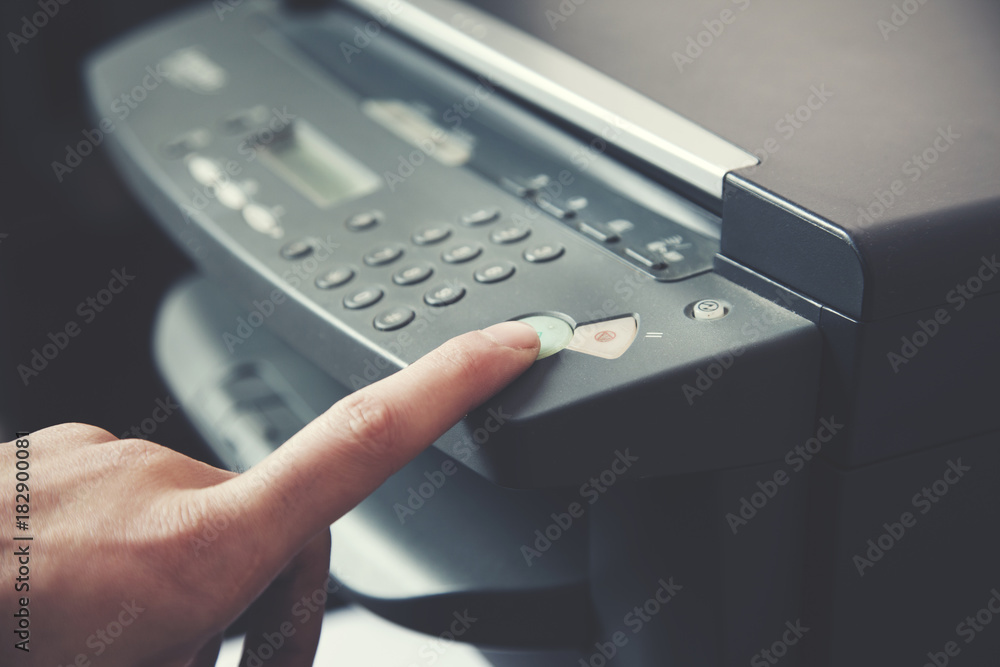 Man holding finger on start button of printer Man holding finger on start button of printer