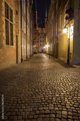 View of cobblestone paving on the empty Kramarska Street and St. Mary s Church at the Main Town  Old Town  in Gdansk  Poland  in the evening.
