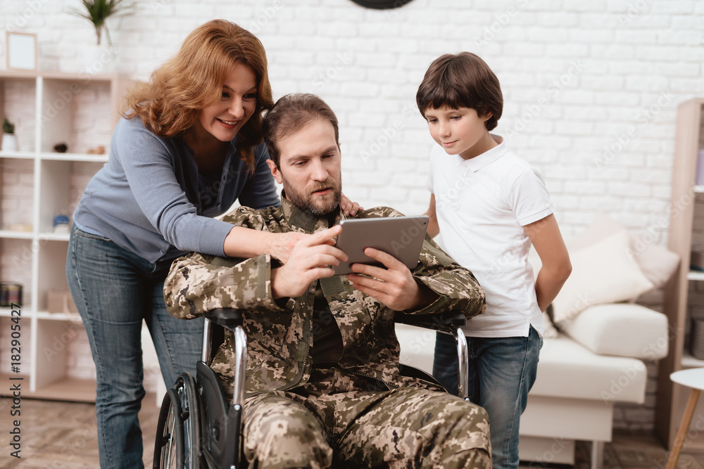 The veteran in a wheelchair came back from the army. A man in uniform in a wheelchair with his family. The veteran in a wheelchair came back from the army. A man in uniform in a wheelchair with his family.