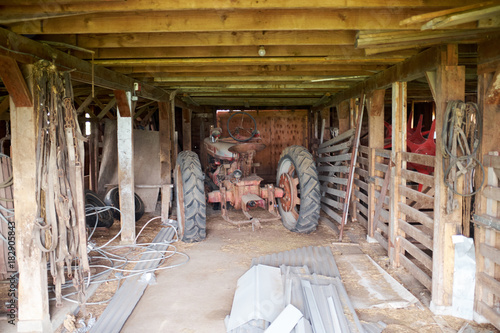 Old tractor parked in a rustic wooden barn
