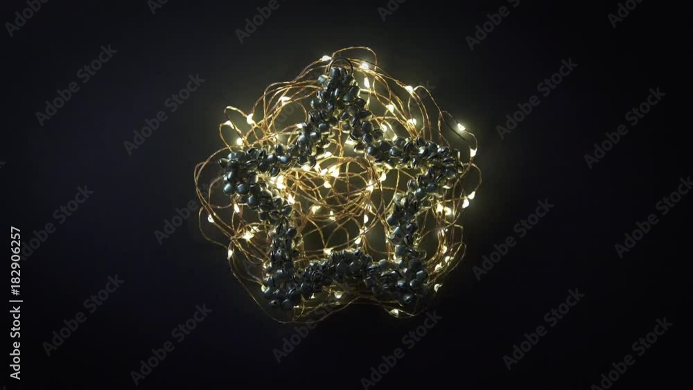 Glowing yellow garland on metal bell decoration on dark background loop. Glowing yellow garland on metal bell decoration on dark background loop.