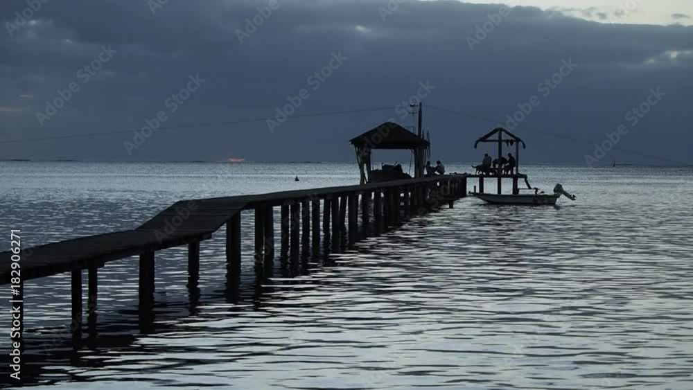People enjoying view from dock at sunset silhouette in French Polynesia Tahiti People enjoying view from dock at sunset silhouette in French Polynesia Tahiti