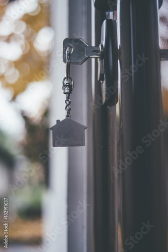House key with pendent in the shape of house in door lock © pawle
