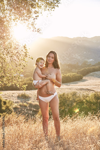 Portrait of pregnant woman and her baby standing outdoors during summer photo