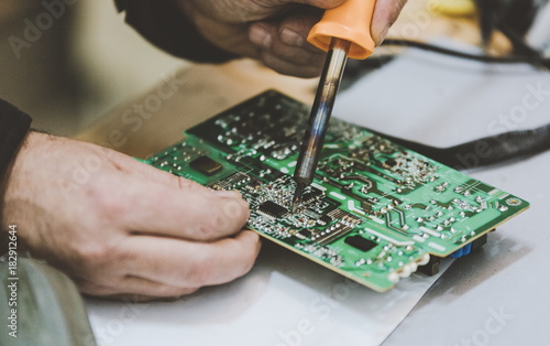 Man Repairing Electronic Circuitr using welder tool photo