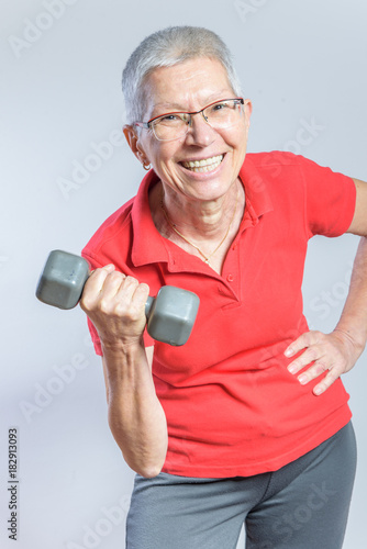 Senior elderly woman lifting weights using dumbbells, exercising and keeping herself in shape