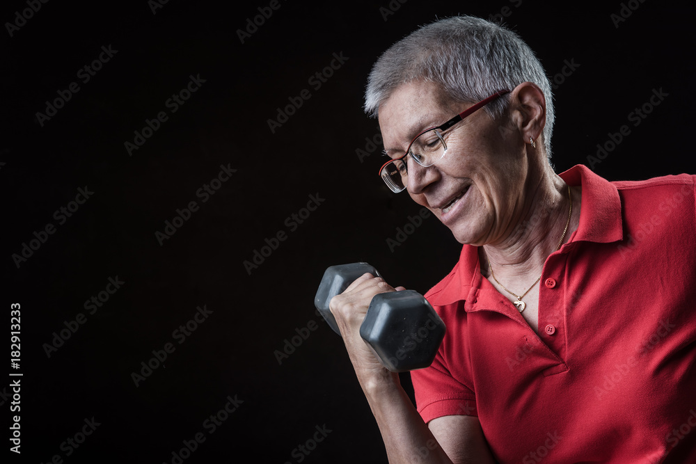 Champion senior lady, lifting weights using dumbbells and feeling strong and powerful; dramatic atmosphere Champion senior lady, lifting weights using dumbbells and feeling strong and powerful; dramatic atmosphere