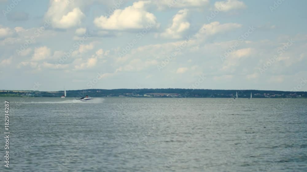 Yachts and a speedboat swim by sea. Luxury yachts and other ships in the city harbor. Gulf in the background of hills, forests and villages. Yachts and a speedboat swim by sea. Luxury yachts and other ships in the city harbor. Gulf in the background of hills, forests and villages.