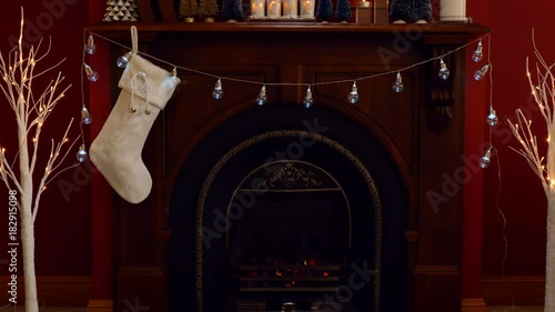 Nightime osy Christmas holiday decorated mantelpiece and fire place in red and white theme, adding Santa Sack full of gfts. photo