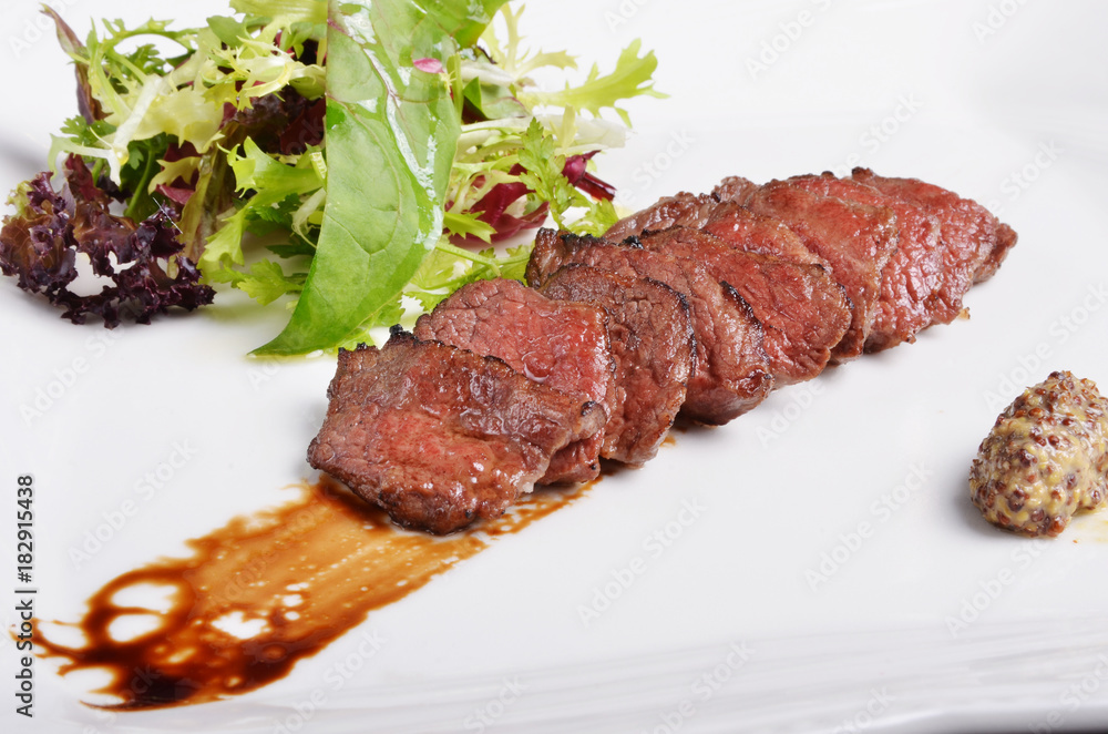 Grilled beef short ribs with salad on white plate Grilled beef short ribs with salad on white plate