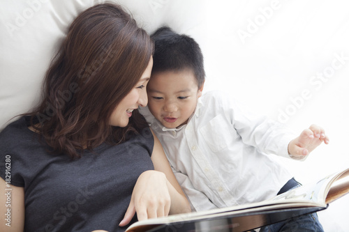 A mother reading a picture book with her son happily