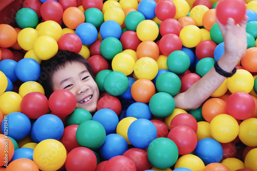 Asian boy having fun in ball pit, indoor play