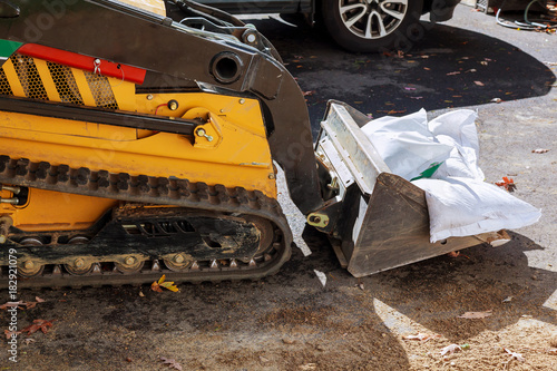 Small excavator removes broken asphalt and gravel on construction s