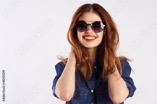Young beautiful woman on a light background in sunglasses, portrait, smile, blank space for copy