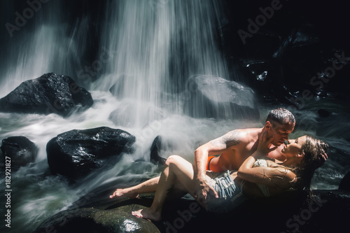 Erotic couple kissing near waterfall. Traveling at Bali.