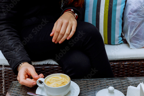 Woman's hands hugging cup of coffee in a restaurant
