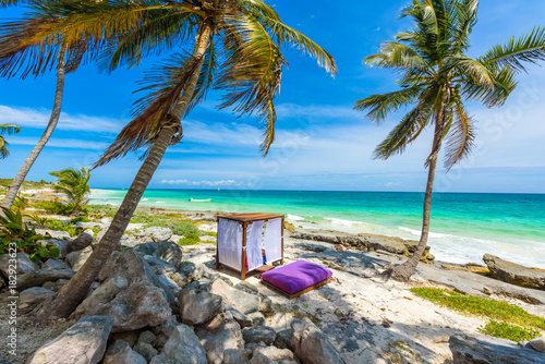 Fototapeta Naklejka Na Ścianę i Meble -  Beach beds under the palm trees on paradise beach at tropical Resort. Riviera Maya - Caribbean coast at Tulum in Quintana Roo, Mexico