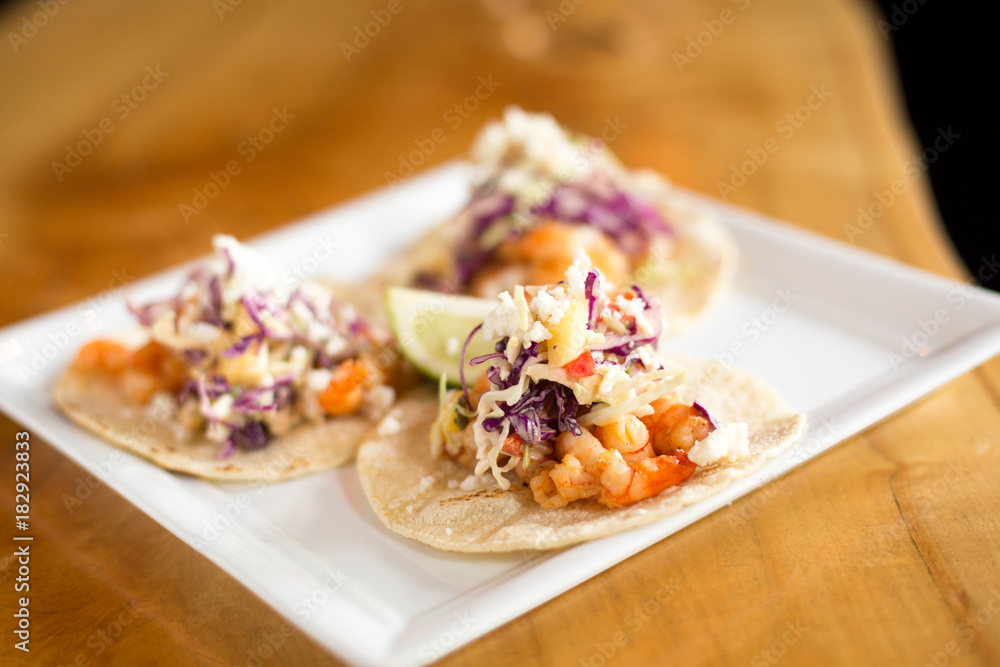 Gourmet fish tacos with coleslaw salsa on a square plate Gourmet fish tacos with coleslaw salsa on a square plate