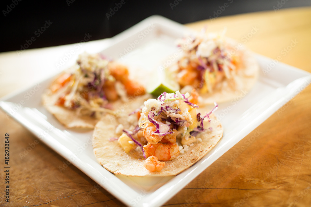 Gourmet fish tacos with mango salsa on a square plate Gourmet fish tacos with mango salsa on a square plate
