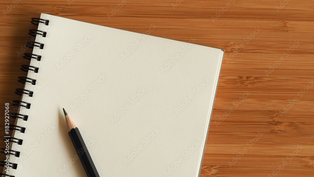 Business and education background with white color book page and black pencil on wood workplace, back to school concept Business and education background with white color book page and black pencil on wood workplace, back to school concept