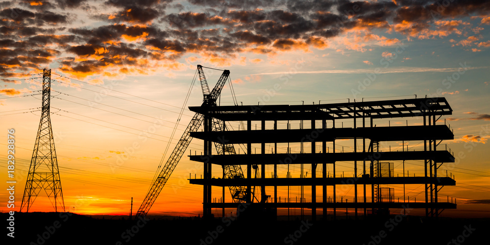 Steel construction site at sunset with a crane.
