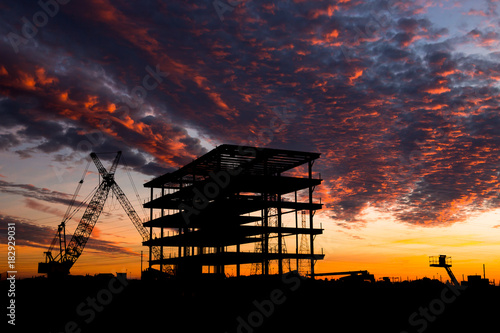 Steel construction site at sunset with a crane.