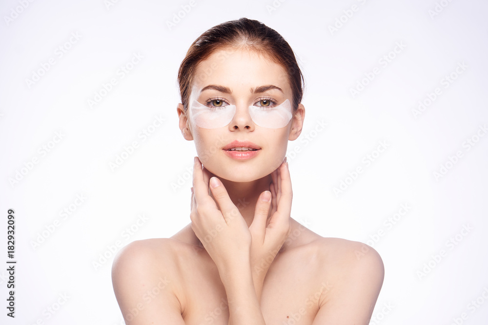 Young beautiful woman in patches for eyes, face care, white isolated background Young beautiful woman in patches for eyes, face care, white isolated background