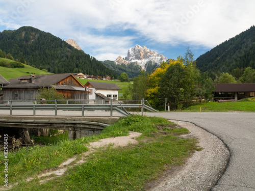 Asphalt road from low point in Alps mountains at hills and mountain village background. Road trip concept, Italy, autumn 2017