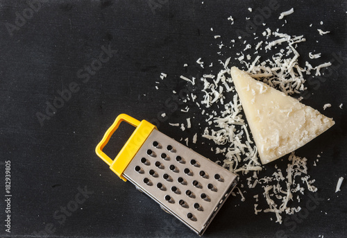 Grated parmesan cheese and grater on wooden background