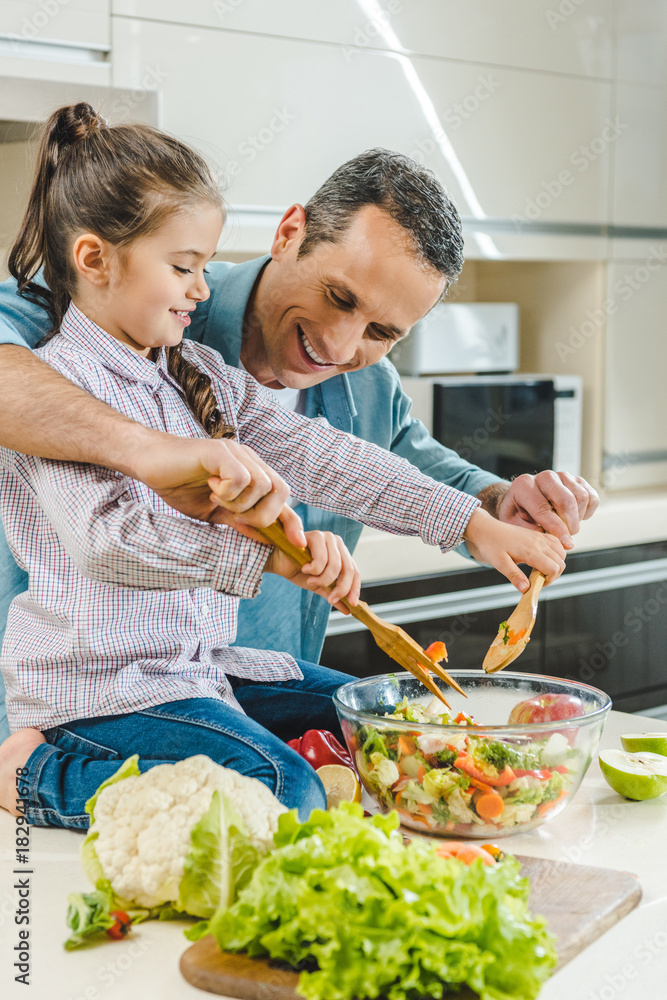 father with daughter mixing salad in bowl father with daughter mixing salad in bowl