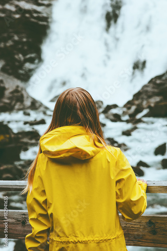 Tourist woman sightseeing waterfall outdoor Travel Lifestyle wanderlust concept adventure vacations in Norway wearing yellow raincoat clothing