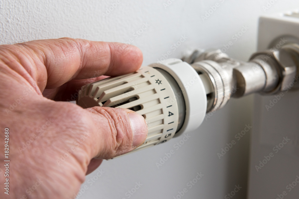 Closeup on man's hand adjusting thermostat valve Closeup on man's hand adjusting thermostat valve